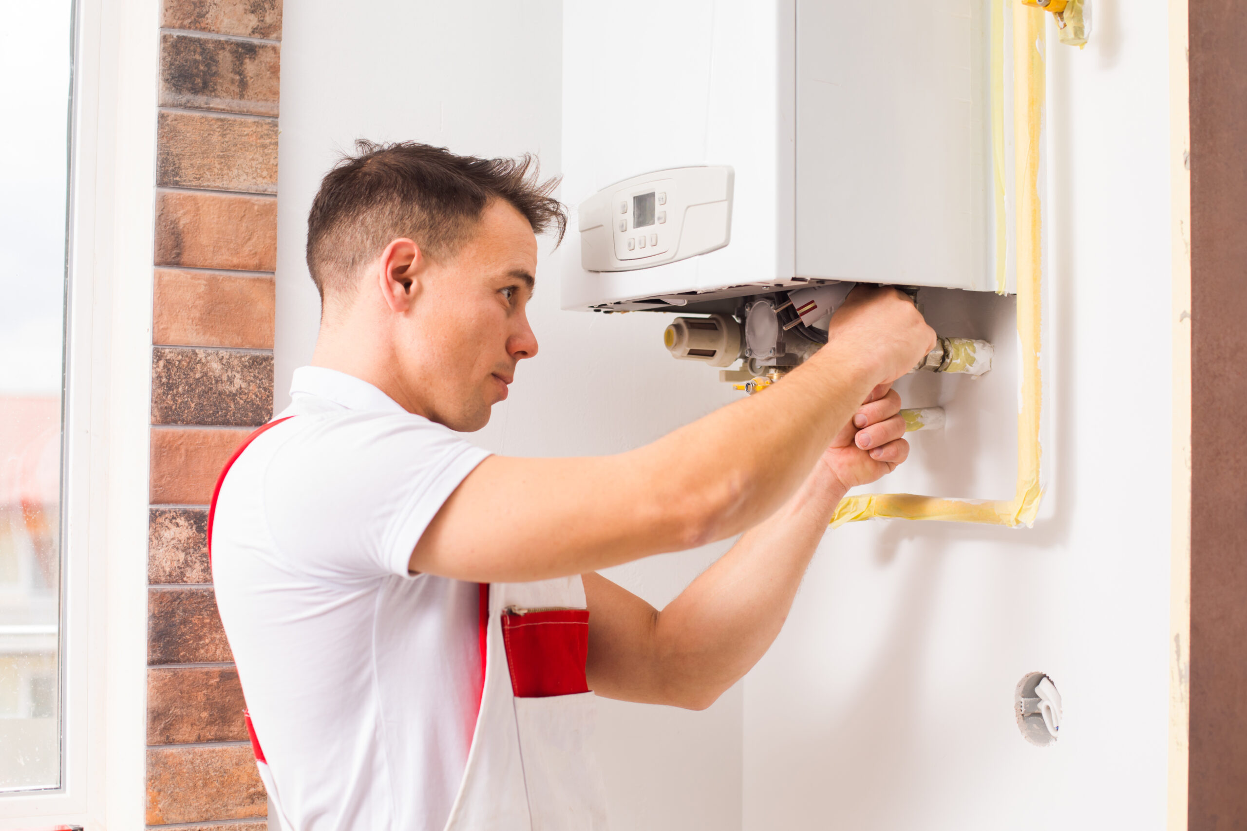 The plumber repairs a boiler at the kitchen boiler cover